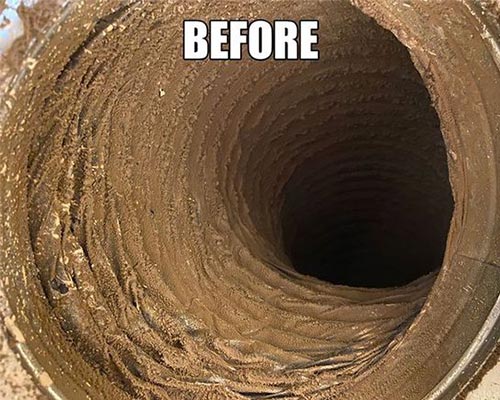 Interior of a residential air duct heavily coated in packed dust and debris before cleaning