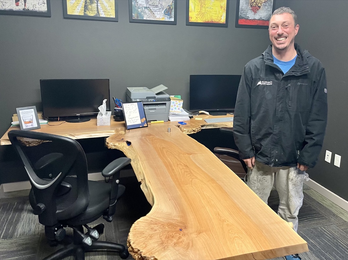 Summit carpenter Justin Finegan with a custom live-edge desk he built