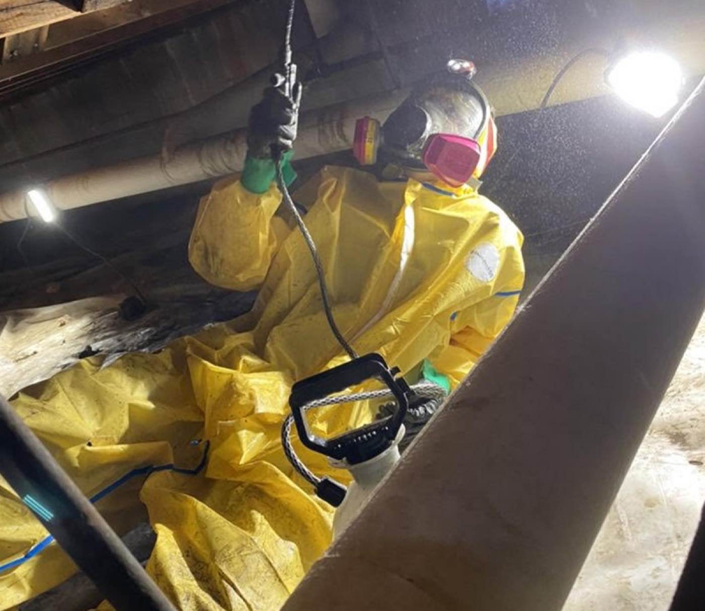 Summit technician in full PPE treating mold in a crawl space
