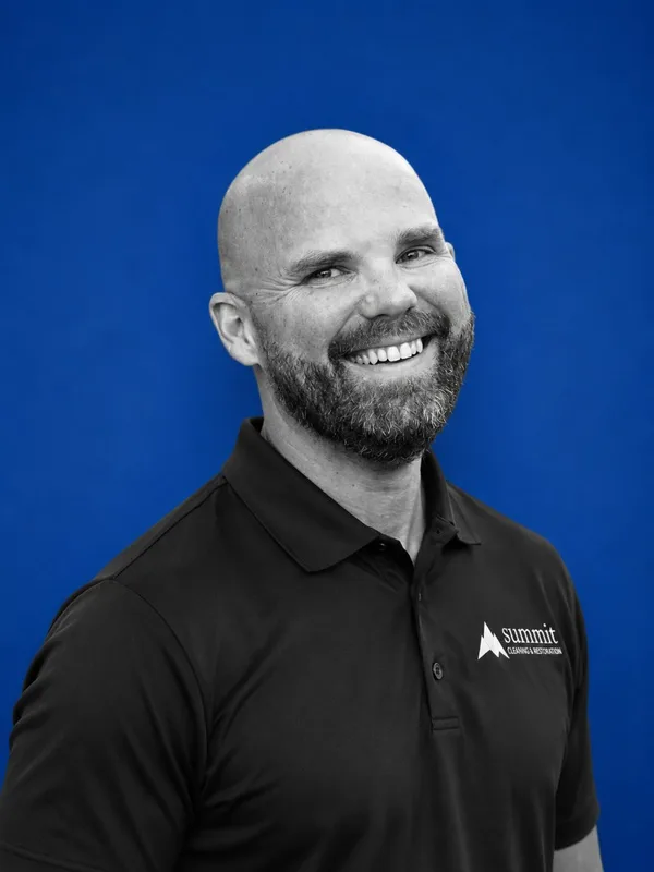 Grandt Mansfield, Director of Marketing & Business Development at Summit Cleaning & Restoration — B&W portrait on Summit cobalt