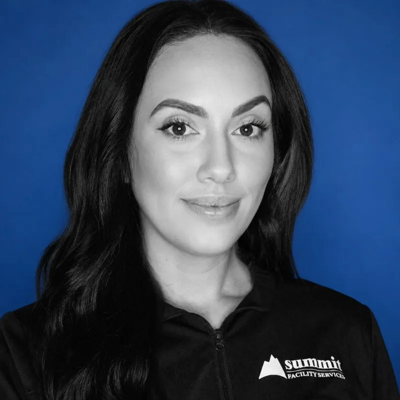 Mariah Rodriguez, Facility Services Director of Operations at Summit Cleaning & Restoration — B&W portrait in a Summit Facility Services zip on Summit cobalt