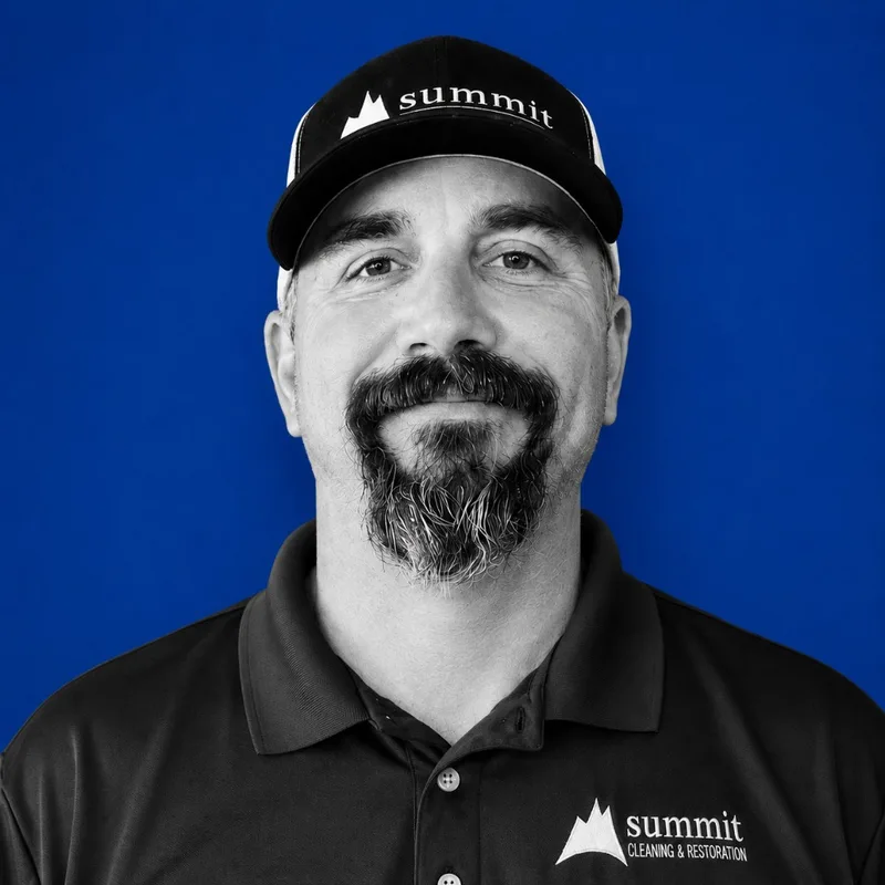 Marty McIntosh, Regional Operations Manager at Summit Cleaning & Restoration — B&W portrait in a Summit cap on Summit cobalt