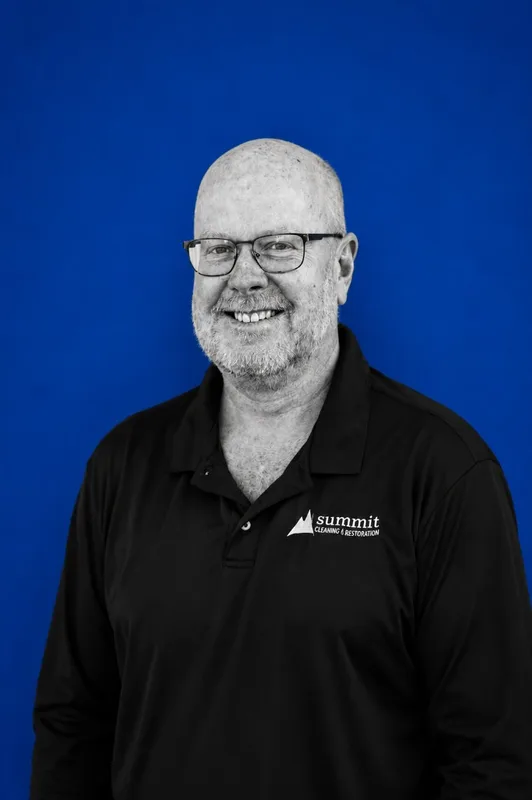 Todd Lane, Director of Operations (Central Oregon) at Summit Cleaning & Restoration — B&W portrait in a Summit cap on Summit cobalt